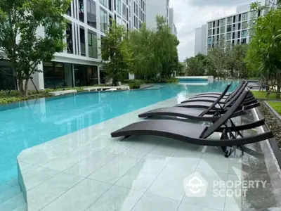 Luxurious condominium poolside with modern sun loungers and lush greenery