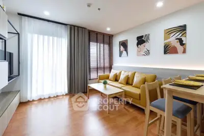 Modern living room with stylish decor and natural light, featuring a cozy yellow sofa and wooden flooring.