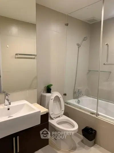 Modern bathroom with sleek fixtures and glass-enclosed bathtub in a contemporary apartment.