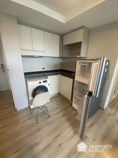 Modern compact kitchen with washing machine and fridge in stylish apartment