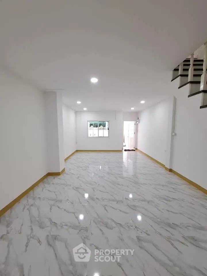 Spacious empty room with glossy marble flooring and staircase, ideal for customization.