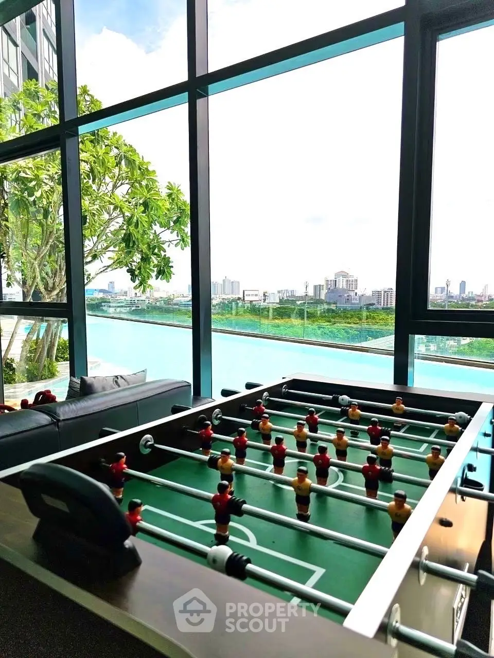 Luxurious high-rise apartment with stunning city view and foosball table in modern living area.