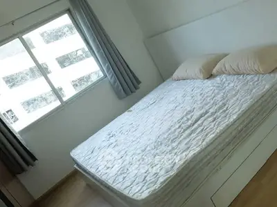 Cozy bedroom with natural light and minimalist design, featuring a comfortable bed and large window.