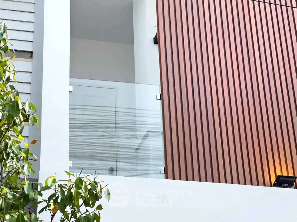 Modern architectural exterior with sleek glass balcony and wood paneling.