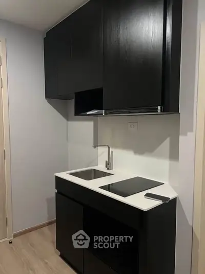 Modern compact kitchen with sleek black cabinetry and built-in stovetop