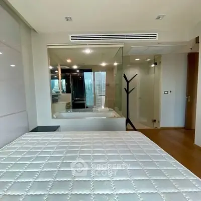 Modern bedroom with glass wall and ensuite bathroom featuring a bathtub.