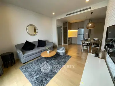 Modern living room with open kitchen, stylish decor, and cozy seating area in a contemporary apartment.
