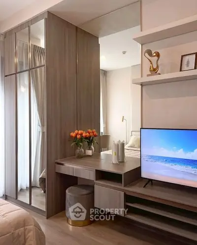 Modern bedroom with stylish decor, mirrored wardrobe, and cozy TV setup.