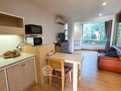Modern living room with open kitchen, featuring stylish furniture and large windows with a serene view.