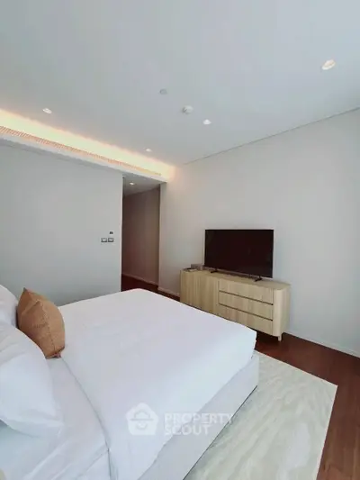 Modern bedroom with sleek design, featuring a large bed, TV, and stylish wooden flooring.