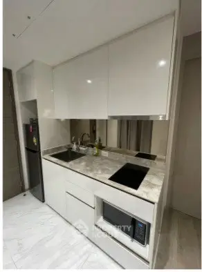 Modern compact kitchen with sleek white cabinets and marble countertops