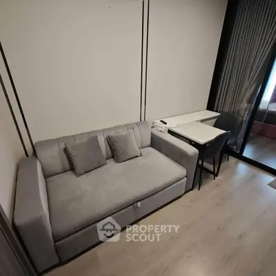 Modern compact living room with stylish gray sofa and small dining table.