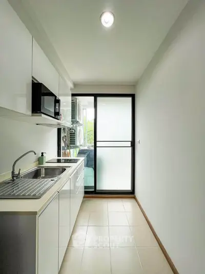Modern kitchen with sleek white cabinetry and large window for natural light