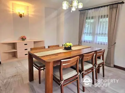 Elegant dining room with wooden table and chairs, featuring stylish lighting and natural light from window.