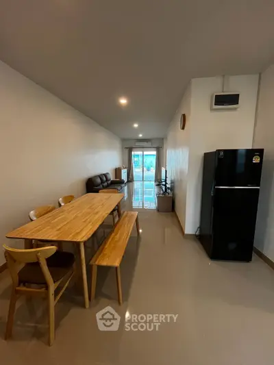 Spacious living room with dining area and modern appliances in a cozy apartment.