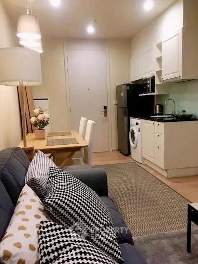Cozy open-plan living room with modern kitchen and dining area, featuring stylish decor and appliances.