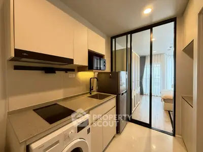 Modern kitchen with sleek appliances and open layout leading to a cozy bedroom.