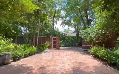 Charming garden entrance with lush greenery and brick pathway leading to a serene home.