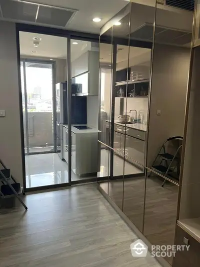 Sleek modern apartment interior with glossy floor tiles, mirrored wardrobe, and a glimpse of an urban balcony view.