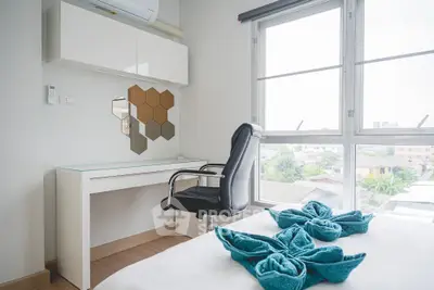 Modern bedroom with stylish desk and city view, featuring elegant decor and natural light.