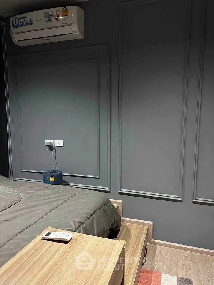 Modern bedroom with sleek gray walls and air conditioning unit, featuring a cozy bed and wooden nightstand.
