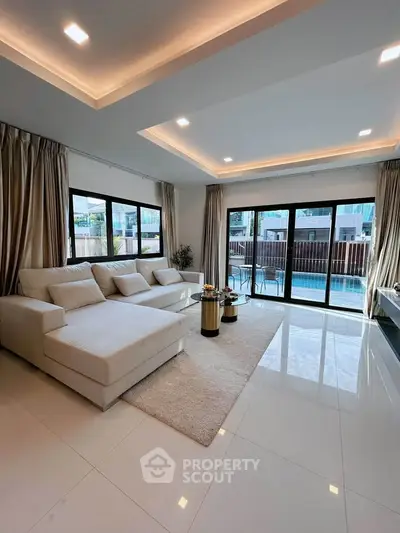 Luxurious living room with pool view, featuring elegant white sofa and modern decor, perfect for relaxation.