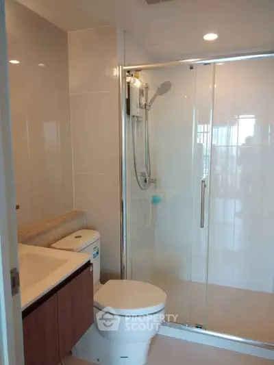 Modern bathroom with glass shower enclosure and sleek fixtures in a contemporary apartment.