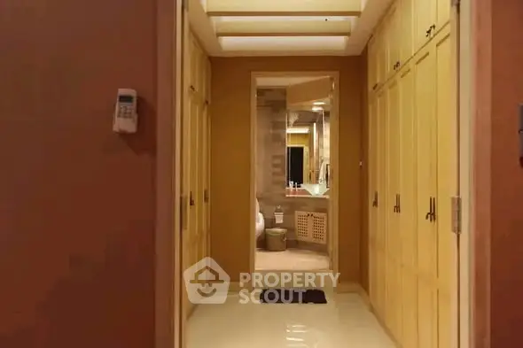 Luxurious hallway leading to a modern bathroom with ample storage space.