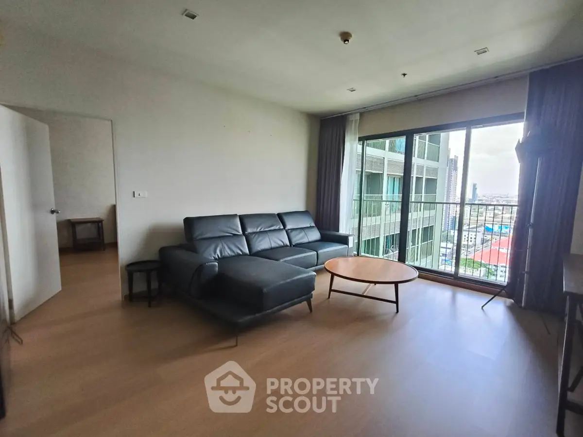 Spacious living room with modern sofa and city view balcony in high-rise apartment