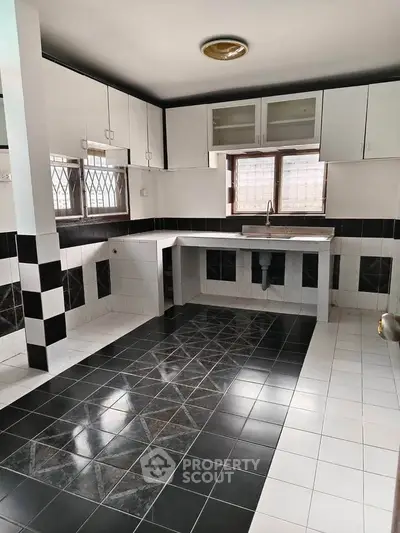 Spacious kitchen with modern black and white tile design and ample cabinet storage.