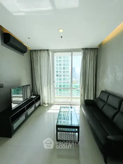 Modern living room with sleek black furniture and city view from large windows.