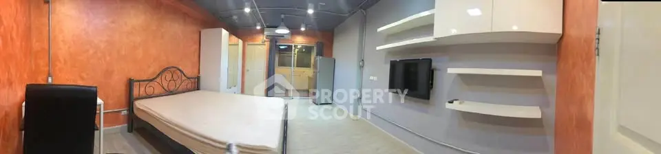 Spacious modern bedroom with stylish shelving and vibrant orange accent wall