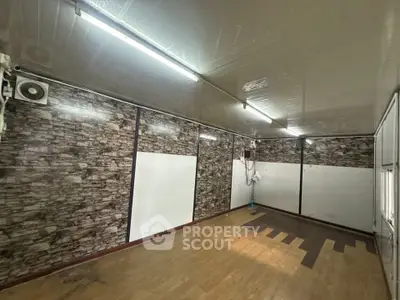 Spacious room with wood flooring and stone accent walls, ideal for versatile use.