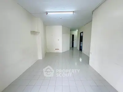 Spacious empty room with tiled flooring and white walls, ideal for customization.