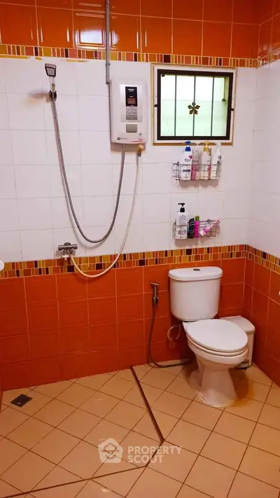 Spacious bathroom with orange tiles and modern shower amenities