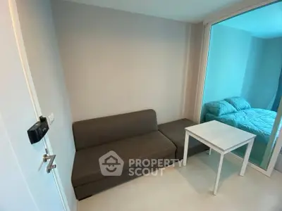 Cozy studio apartment with compact living area and bedroom separated by glass partition.