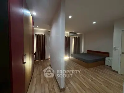 Spacious bedroom with wooden flooring and ample natural light