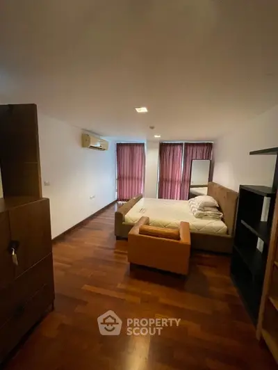 Spacious bedroom with wooden flooring and large windows for natural light