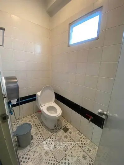 Modern bathroom with stylish tile flooring and compact design, featuring a window for natural light.