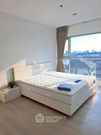 Bright and airy bedroom with large window offering stunning city views, modern furnishings, and elegant decor.