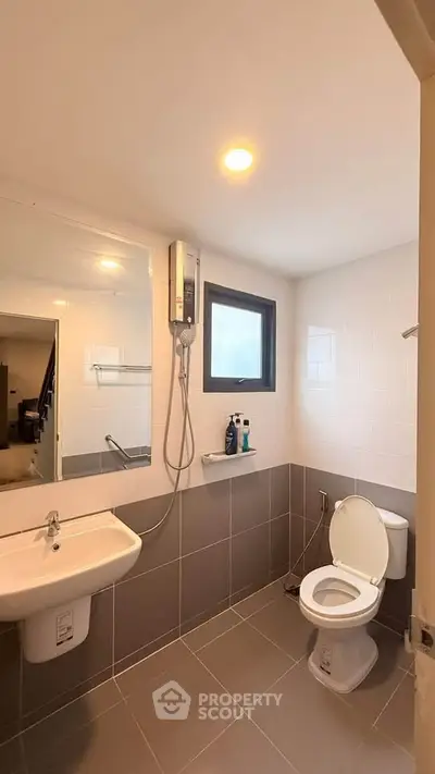 Modern bathroom with sleek design, featuring a shower, toilet, and sink in a well-lit space.