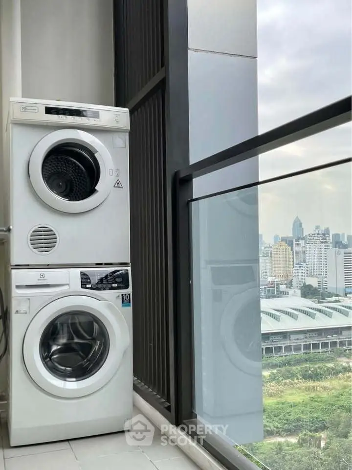 Modern high-rise balcony with city view and stacked washing machines.