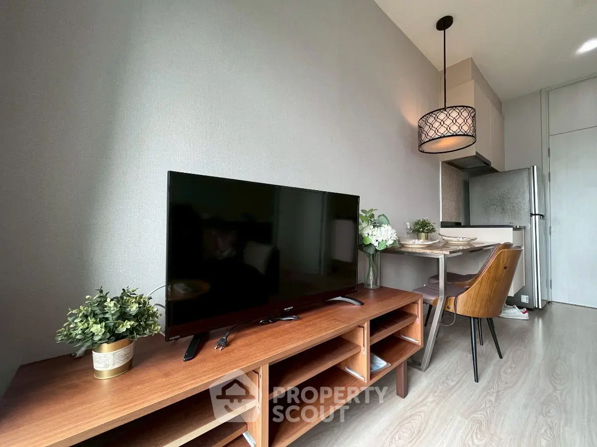 Modern living room with sleek TV stand and cozy dining area in stylish apartment.