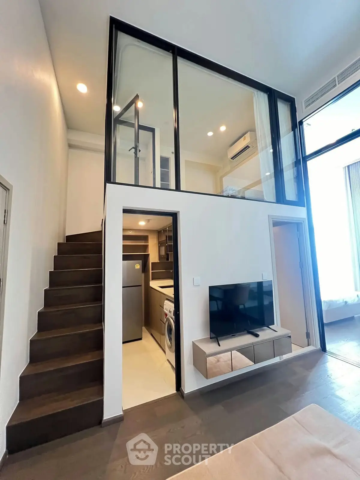 Modern loft apartment with mezzanine, sleek staircase, and stylish living area featuring a TV and appliances.