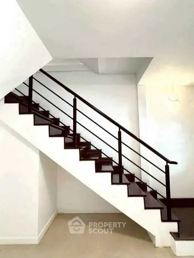 Modern staircase with sleek black railing in a minimalist interior setting.