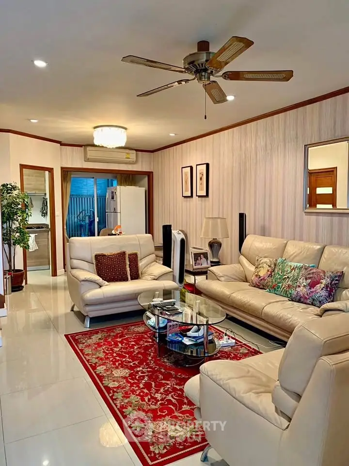 Elegant living room with plush leather sofas and a stylish ceiling fan.