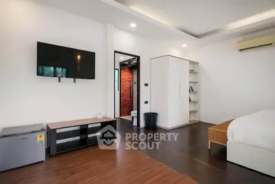 Spacious modern bedroom with wall-mounted TV and sleek wooden flooring