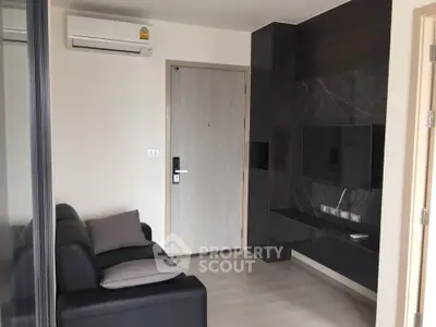 Modern living room with sleek black sofa and wall-mounted TV in stylish apartment.