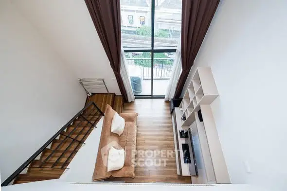 Modern loft-style living room with high ceiling and large windows offering a stunning view.