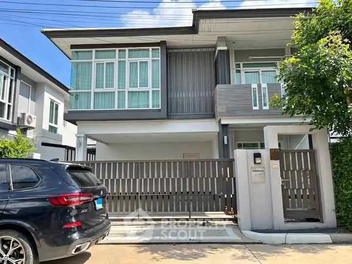 Modern two-story house with sleek design and spacious driveway in a suburban neighborhood.